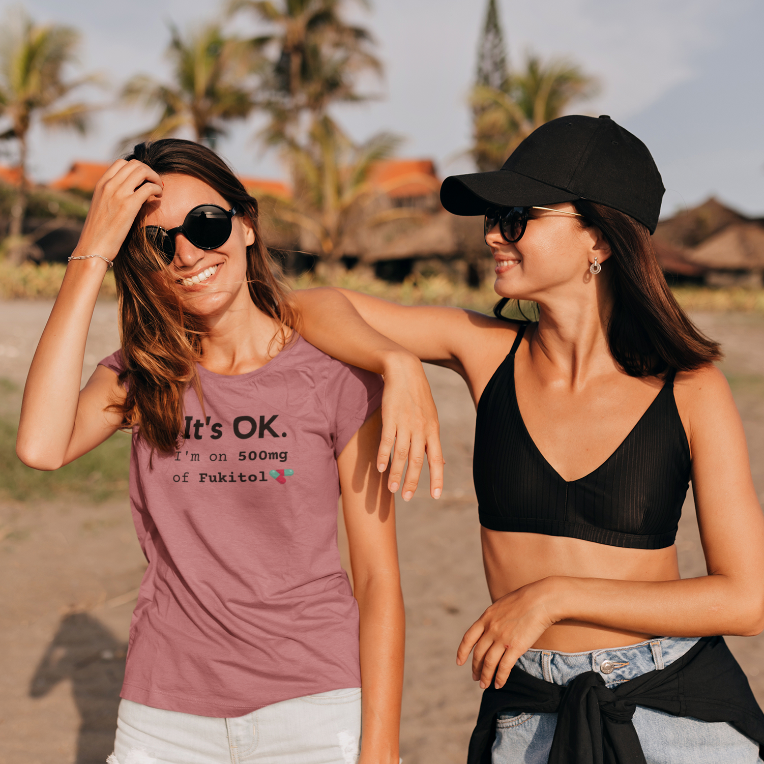 Funny workout shirt with text I'm on 500mg of fukitol, tee in heather mauve almost pink or rose gold color worn by a woman enjoying a walk at the beach with a female friend