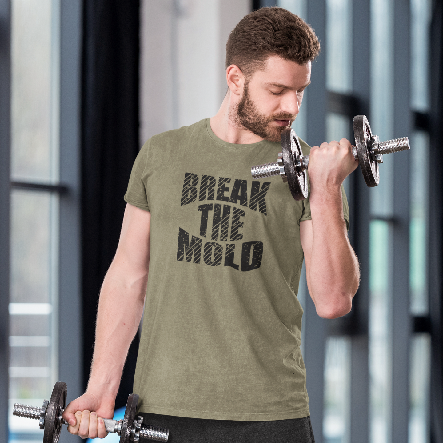Motivational gym shirt with text "Break The Mold", the graphic workout shirt is worn by a bearded middle age man doing bicep curls at the gym.