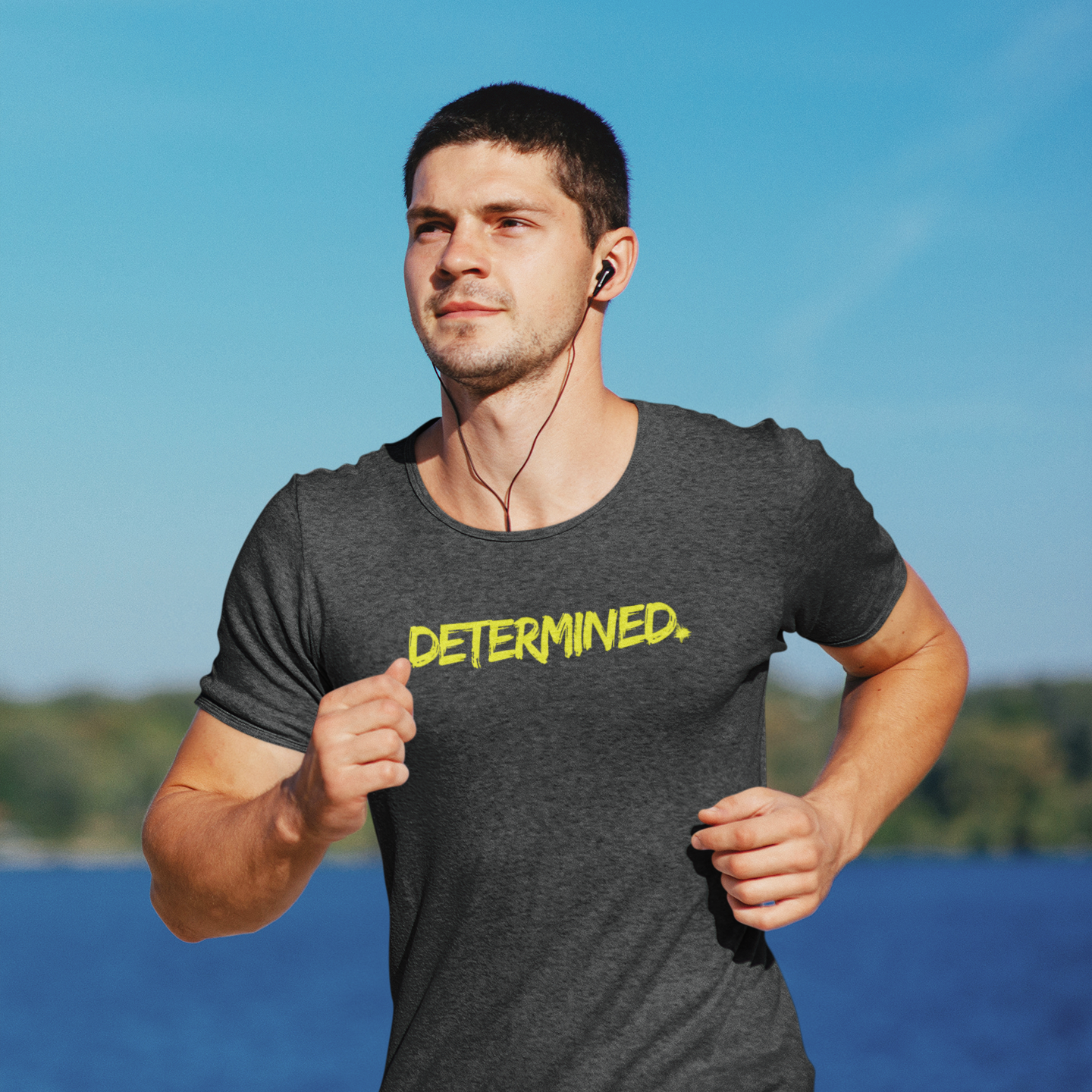 Motivational workout shirt in dark grey heather almost black color and yellow letters worn by a young man running outdoors